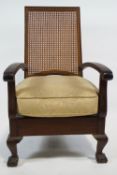 An armchair with caned back and upholstered seat on cabriole legs with ball and claw feet,