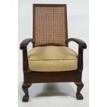 An armchair with caned back and upholstered seat on cabriole legs with ball and claw feet,