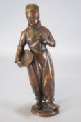 An early 20th century bronze of a Dutch fisher boy holding a basket in one hand a pipe in another,