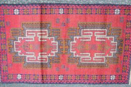 A natural dye hand made Afghan Baluchi rug, with two medallions on a red field within two borders,
