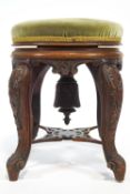 A Victorian mahogany piano stool on four carved legs linked by a pierced stretcher,