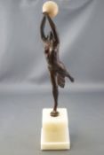 An Art Deco style bronze patinated figure of a dancing lady holding an ivorine ball aloft,