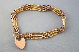 A yellow metal three bar gate bracelet. Padlock clasp with fitted safety chain.