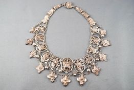 A Burmese silver-like metal collar formed with graduated plaques each set with a deity,