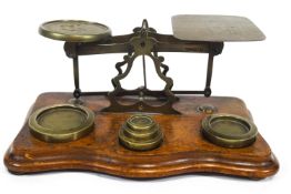 A set of Victorian brass postal scales and weights on a shaped mahogany base,