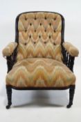 A Victorian button back armchair, with ebonised show frame, on turned tapering legs and casters,