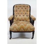 A Victorian button back armchair, with ebonised show frame, on turned tapering legs and casters,