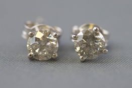 A white metal pair of single stone stud earrings.