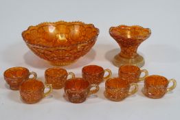 A carnival glass punch bowl on stand, with six matching cups,