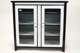 A 1950's white enamel cabinet with black enamel banding,