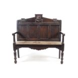 An oak hall bench with carved armorial on the cresting above a quadrupled panelled back
