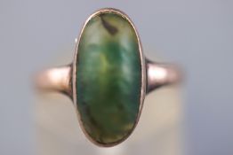 A yellow metal ring set with an oval cabochon nephrite jade measuring approximately 15.3mm x 7.7mm.