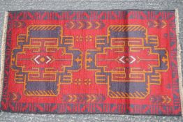 A natural dye hand made Afghan Baluchi rug, with two medallions on a red field within one border,