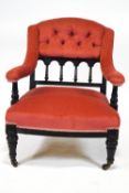 A late Victorian armchair with ebonised frame, button back,