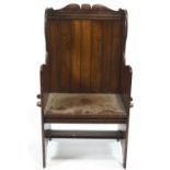 An oak lambing chair, with slatted back, shaped sides and plank seat,