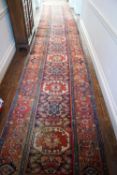 A Caucasian runner with seven medallions on a patterned blue ground with a wide border 600cm x 104cm