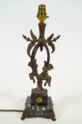 A cast metal and marble table lamp, in the form of two cherubs sitting on a scrolling branch,