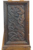 An oak panel carved with two interlocking snakes with dragon heads,