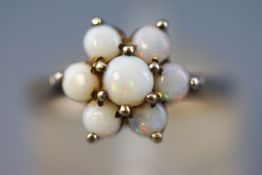 A yellow metal cluster ring set with seven circular cabochon cut opals of commercial quality.