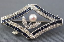 A white metal abstract design brooch set with calibre cut sapphires