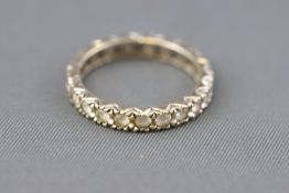 A white metal full eternity ring set with colourless synthetic spinel.