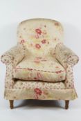 An armchair upholstered with flower sprays on a cream ground on turned tapering legs legs,