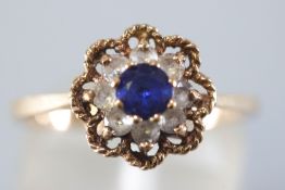 A yellow metal cluster ring set with blue and white synthetic stones.