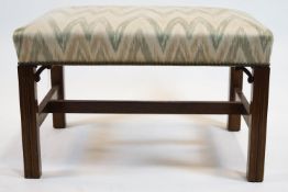 A rectangular foot stool on George III style mahogany legs linked by an H stretcher,