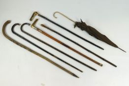 A collection of six assorted walking sticks and a lady's umbrella to include an ebonised example,