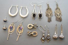 A collection of eight pairs of sterling silver earrings of variable designs.