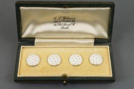 A collection of four white enamelled waistcoat buttons.