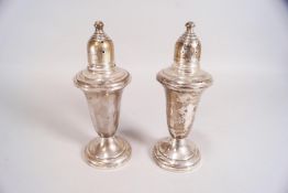 A pair of white metal glass lined urn shaped peppers with screw off covers,