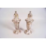 A pair of white metal glass lined urn shaped peppers with screw off covers,