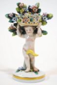 A Sampson figure of a Putto supporting a basket of flowers, circa 1900, gilt anchor mark,