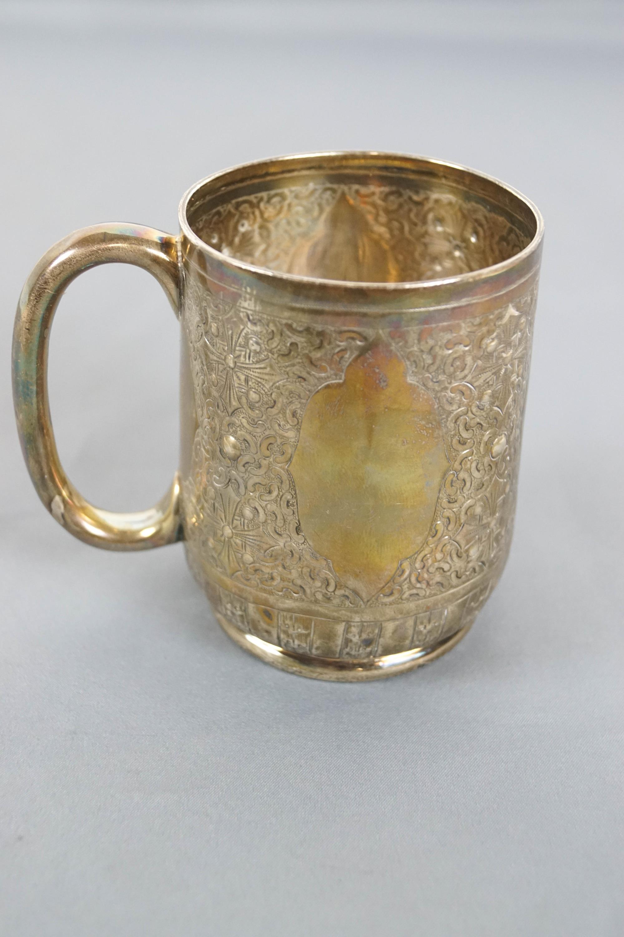 A small silver mug, of rounded form, decorated with engraved quatrefoils and strapwork,