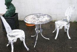 A cast aluminium garden table and two chairs, painted white in Victorian style,