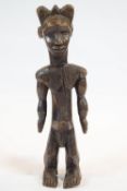 An African large carved wood fetish figure, modelled standing and carved with hatched ornament,