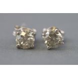 A white metal pair of single stone stud earrings.