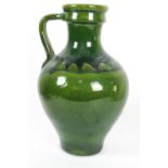 A terracotta green glazed large oriform jug with strap handle with shoulder incised with a band