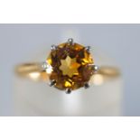 A yellow and white metal single stone ring set with a round faceted cut citrine quartz.