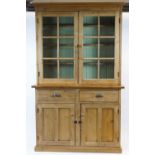 A pine dresser with two glazed doors above two drawers and two cupboard doors, on plinth base,