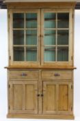 A pine dresser with two glazed doors above two drawers and two cupboard doors, on plinth base,