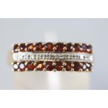 A yellow metal three row half hoop ring set with two rows of garnets