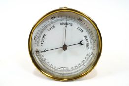 An aneroid barometer, of cylindrical form, with enamel dial enclosing a temperature gauge,