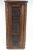 A carved oak corner cabinet, constructed with three 17th century panels to the door,