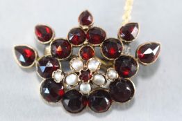 A yellow metal abstract brooch set with rose cut pear and round garnets
