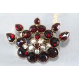 A yellow metal abstract brooch set with rose cut pear and round garnets