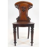 A Victorian mahogany hall chair with foliate carved back, with shield on turned legs,