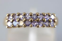 A yellow metal half hoop ring set with two rows of round faceted cut pale colour tanzanite.