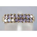 A yellow metal half hoop ring set with two rows of round faceted cut pale colour tanzanite.